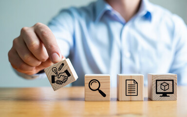 Hand placing wooden block with handshake and lightbulb icons representing business deal and creative idea on a table with search document and design icons