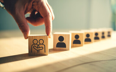 Hand placing a wooden block with a teamwork icon in a row of blocks representing individuals symbolizing collaboration and building a strong team for business success