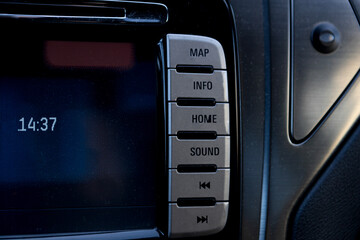 Dashboard controls displaying map, info, home, and sound settings in a modern vehicle at afternoon time