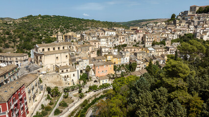 Naklejka premium Aerial view of the buildings, houses and apartments, ideal for the concept of an Italian hilltop village nestled among the mountains. This is the historic center of Ragusa Ibla, Sicily, Italy.