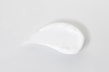 Swatch of white cream on white background, top view