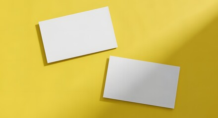 Two blank white business cards mockup flat lay on a yellow background with sunlight shadow