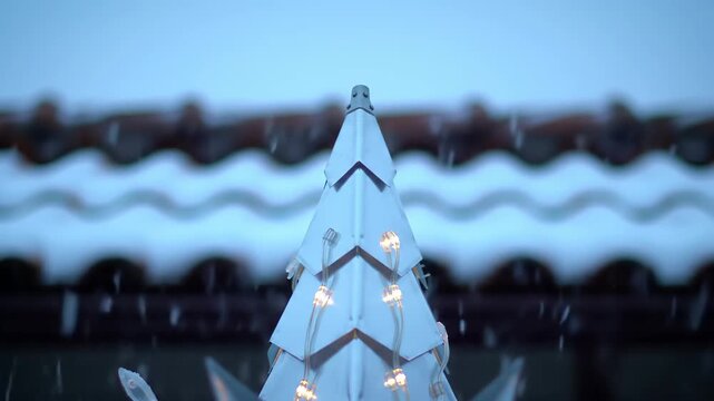 Minimalist Christmas Tree Topper with Warm White Lights Against Blurry Roofline in Winter Evening