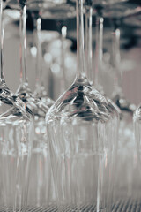 rows of clean upside-down wine glasses arranged on a shelf and illuminated with soft pink lighting. The reflective glass surface creates a modern, stylish atmosphere suitable for themes related to res