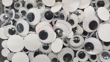 Googly eyes scattered craft supplies, creative background texture