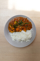 A plate of chicken curry with white rice.