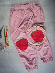 Children&rsquo;s corduroy trousers with a strawberry-shaped patch and embroidered leaves, showing creative upcycling, visible mending and sustainable fashion that gives kids&rsquo; clothing a second life