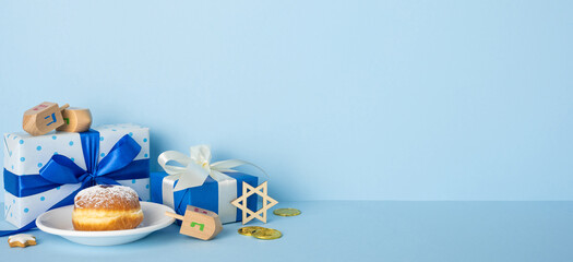 Blue Hanukkah banner scene featuring gifts, a plate with a doughnut, dreidel, Star of David, coins,...