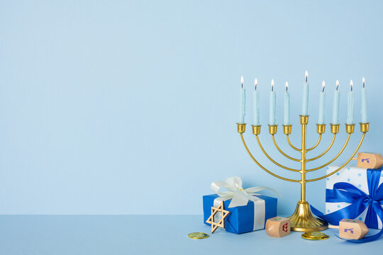 Blue and gold Hanukkah scene featuring a lit menorah, wrapped gifts, and a dreidel. Festive, warm, and traditional, this image captures holiday lighting, gift wrap, and cultural symbolism - Powered by Adobe