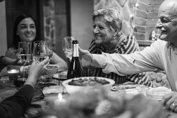 Happy family celebrating Christmas holidays while cheering with champagne at home - Winter vacation, bonding, love and dinner concept - Main focus on right man hand