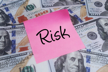 Financial Risk Warning Pink sticky note with Risk on scattered US dollar bills, symbolizing investment uncertainty and economic caution