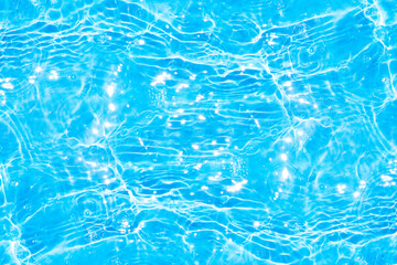 Blue water with ripples on the surface. Defocus blurred transparent blue colored clear calm water surface texture with splashes and bubbles. Water waves with shining pattern texture background.