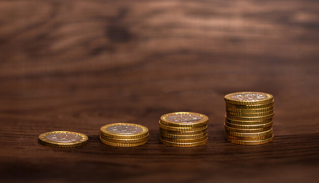Stacks of Costa Rican 500 colones coins arranged in ascending order on wood, symbolizing financial growth, savings, and economic progress.