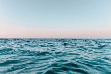 Obraz premium The serene waters stretch endlessly towards the horizon, meeting a clear blue sky. The gentle waves create a soothing atmosphere perfect for relaxation