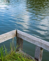 Fototapeta premium Wooden pier corner overlooking calm lake with water lilies and cloud reflections