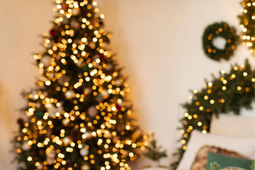 Blurred shot of warm and inviting holiday setting featuring sparkling Christmas tree adorned with lights, wall decorated with green wreaths, creating festive atmosphere