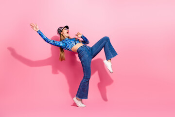 Glamorous young woman model dancing in pink background showcasing casual fashion style and joyful energy