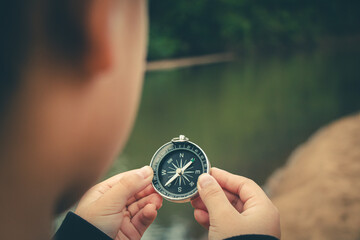 Person standing holding compass reflective travel moment with a compass and sea horizon merging under the golden sky.