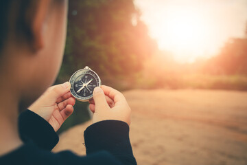 Person standing holding compass leads the way across the calm ocean at sunset.