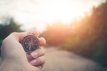 Traveler&rsquo;s compass shining softly under the warm colors of the sunset by the shore.