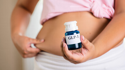 GLP-1 supplement held by woman in pink top focusing on weight management or health awareness campaigns, diabetes management, metabolic health research, weight control