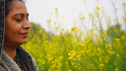 Female farmer inspecting healthy black mustard crop in rural India. South Asian woman among...