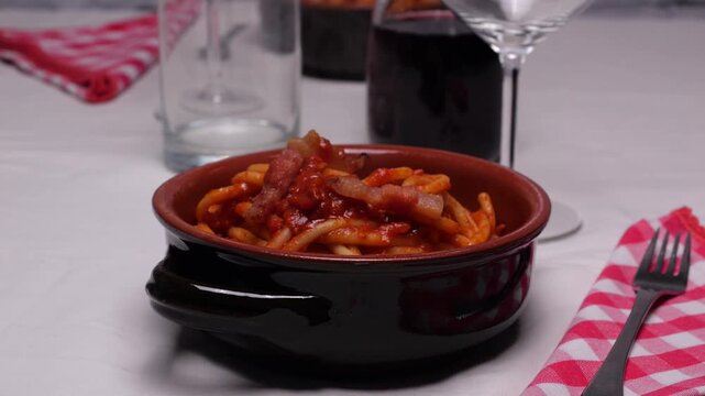 Persona mette i pezzetti di guanciale sulla pasta 