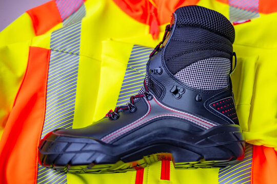 black heavy-duty work boots, strong yellow work jacket, prominent reinforced steel toe, essential PPE construction, special shoes, safety equipment, hard labor, workplace compliance, hard labor