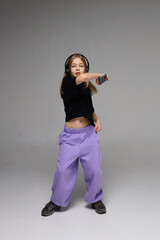 Young caucasian girl dancing with headphones and controller in studio setting