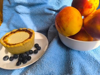 freshly baked bun with sour cream filling on a white plate surrounded by ripe nectarines.
