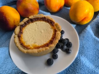 freshly baked bun with sour cream filling on a white plate surrounded by ripe nectarines.
