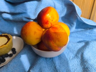 freshly baked bun with sour cream filling on a white plate surrounded by ripe nectarines.