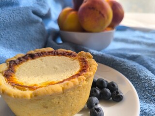 freshly baked bun with sour cream filling on a white plate surrounded by ripe nectarines.