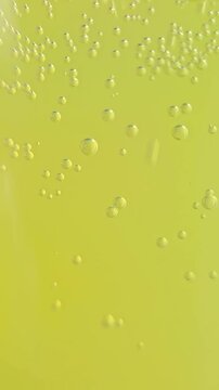 Close-up view of yellow sparkling drink surface with bubbles and carbonation. textured surface of a carbonated yellow beverage with rising bubbles and fizz. 