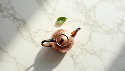 Copper teapot with leaf on marble countertop in bright sunlight  