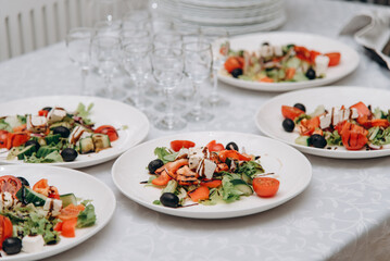 Greek salad in plates on white table in banquet hall