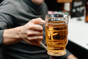 beer glass in man hand in bar, cheers, selective focus, close-up view