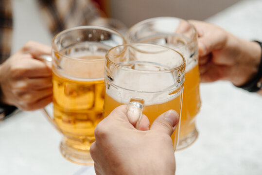 clinking glasses of beer, company of friends in bar, three men and three glasses of beer - Powered by Adobe