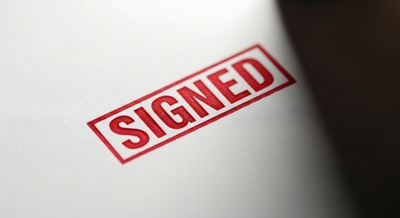 Signed Agreement: Close-up of a bold SIGNED stamp on a white document, conveying official approval and legal validity.