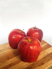 Close-Up of Three Ripe Red Gala Apples with Stems, White and Wood Background, Clean