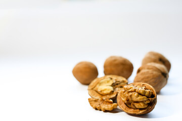 Whole and peeled brown walnuts on the white background