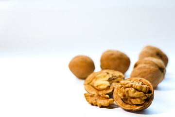 Whole and peeled brown walnuts on the white background