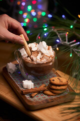Hand Adding Cookie Stick to Hot Chocolate with Marshmallows