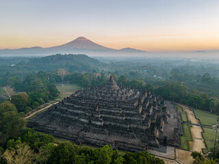 Aerial view of Borobudur Temple in Central Java, Indonesia. Ancient Buddhist monument at sunrise, with Merapi volcano in the background. UNESCO World Heritage Site, culture, history, and travel themes © JKVisuals