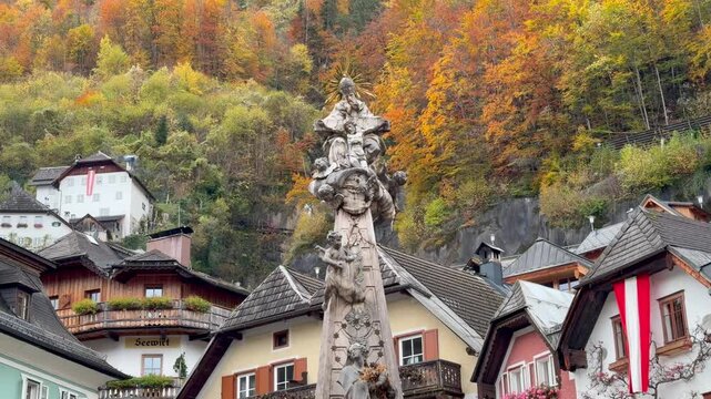 Baroque Trinity Column with Angels and Alpine Houses with Austrian Flag and Autumn Forest in Hallstatt Town Square Austria 4K