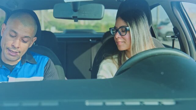 Male driving instructor explaining the rules of the road to a young female student driver