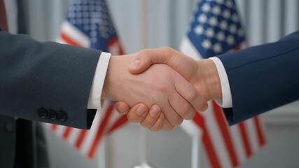Two businessmen shaking hands in front of American flags, symbolizing a deal or agreement. - Powered by Adobe