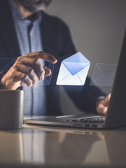 Professional Working Late at Night Interacting with a Glowing Virtual Email Icon on a Modern Laptop Device