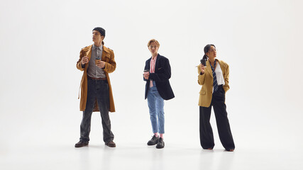 Group of creative young professionals in stylish coats holding coffee cups during morning...