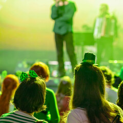 Girls in festive green accessories watching live performance at St. Patrick Day party in nightclub....